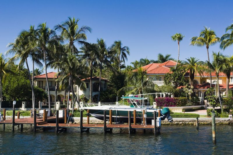 Luxury waterfront homes with palm trees and a boat docked in Fort Lauderdale, Florida.