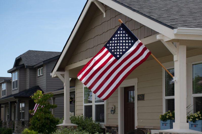 Vibrant American flag waving outside a stylish suburban house in daylight.
